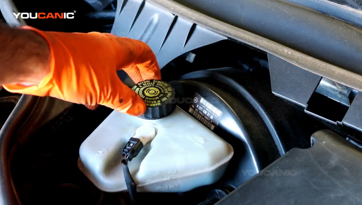 Removing the brake fluid cap.