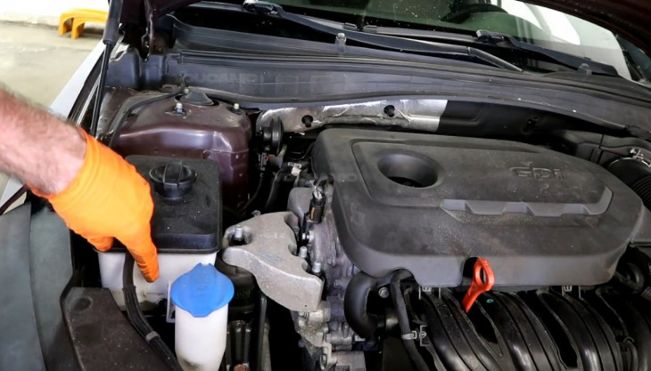 Checking the coolant level on the reservoir tank of the 2016-2020 Kia Optima.